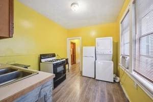 2226 Saint Bernard Ave, New Orleans, LA 70119 - kitchen with range with gas cooktop, freestanding refrigerator, wood finished floors, light countertops, and cooling unit