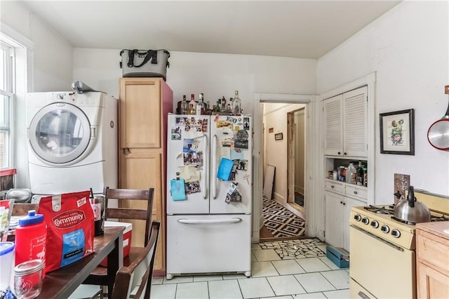 2226 Saint Bernard Ave, New Orleans, LA 70119 - kitchen with white appliances, stacked washing machine and dryer, light tile patterned floors, and light brown cabinets
