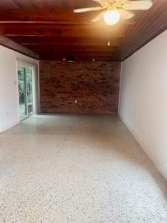 unfurnished room featuring ceiling fan, brick wall, and wooden ceiling