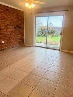 tiled empty room with ceiling fan and brick wall