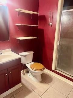 bathroom with toilet, vanity, tile patterned floors, and a shower with shower door