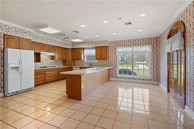 kitchen with gas stovetop, light tile patterned floors, ornamental molding, and white fridge with ice dispenser