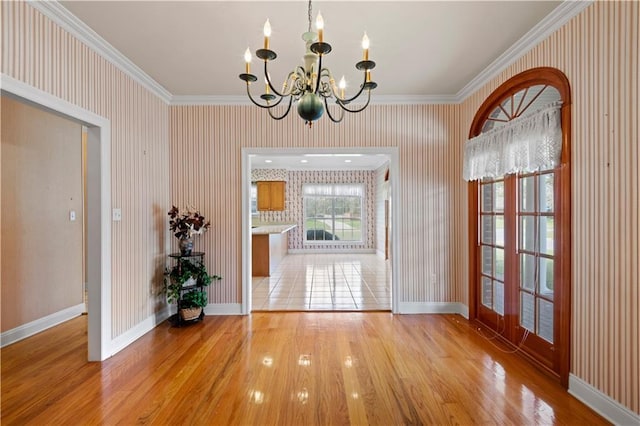 entryway with ornamental molding, wood-type flooring, and a notable chandelier