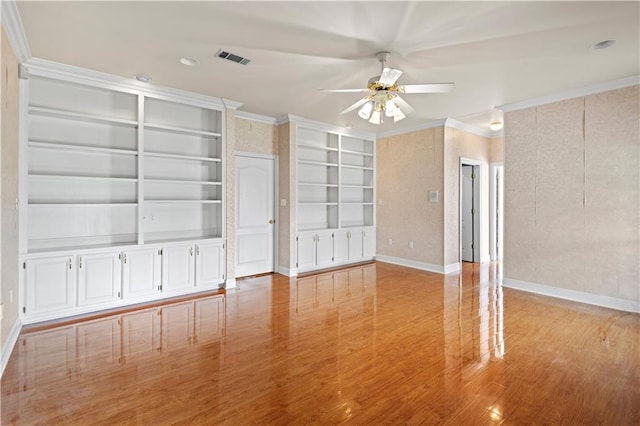 spare room featuring crown molding, ceiling fan, built in features, and light wood-type flooring