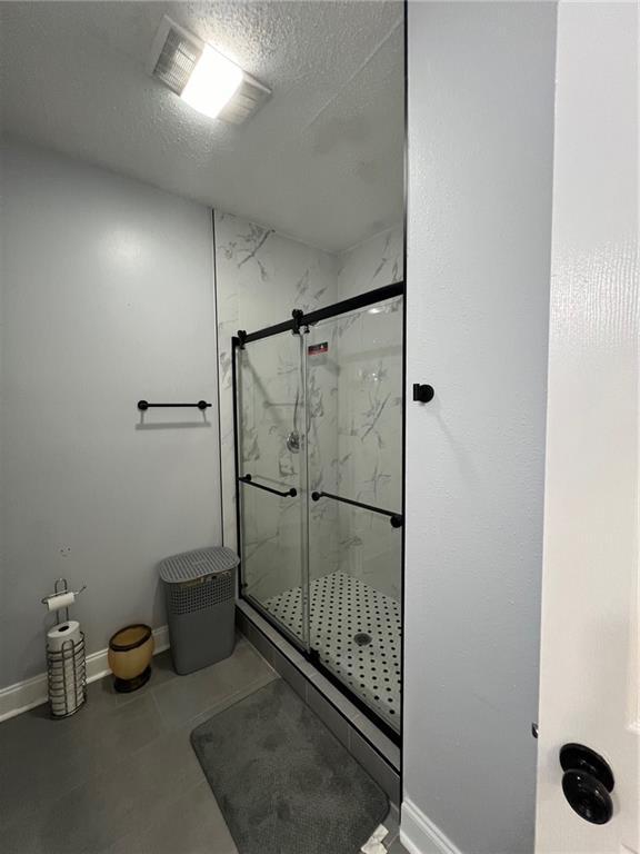 bathroom featuring a shower with door and a textured ceiling