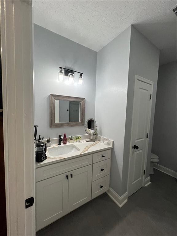 bathroom with vanity, a textured ceiling, and toilet