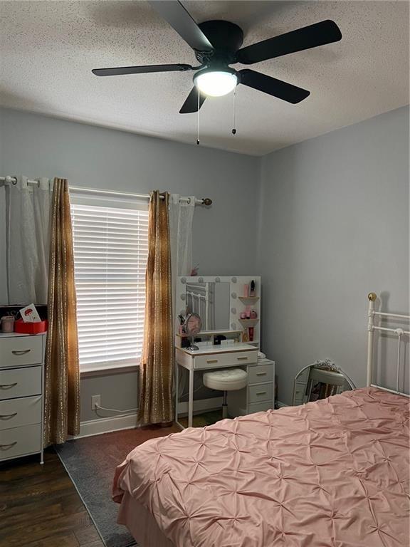 bedroom with dark wood-type flooring, ceiling fan, and a textured ceiling