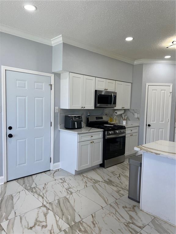 kitchen featuring white cabinetry, ornamental molding, and appliances with stainless steel finishes