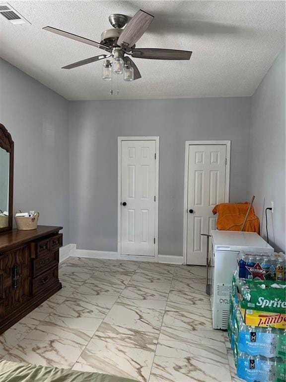 bedroom with ceiling fan and a textured ceiling