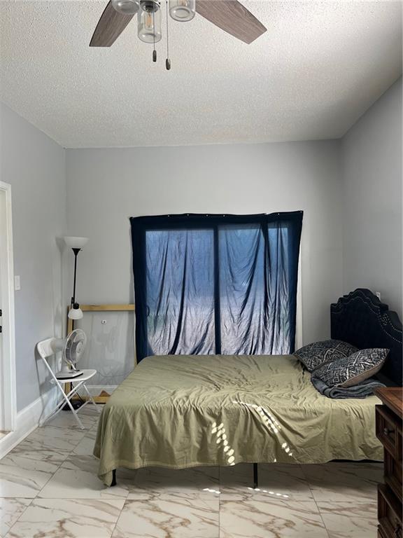 bedroom featuring ceiling fan and a textured ceiling