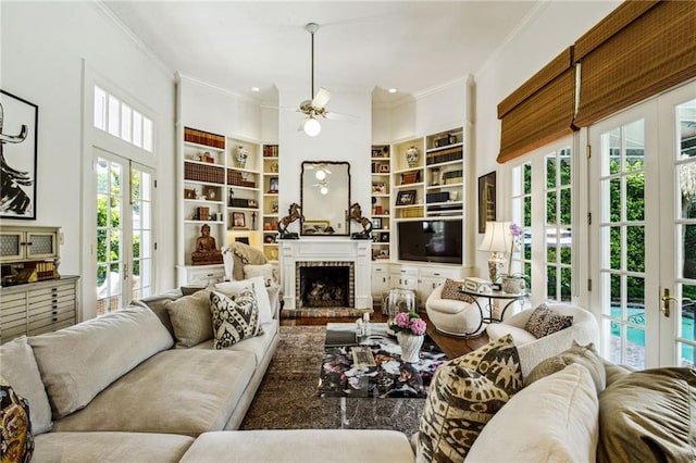 living room with a brick fireplace, ornamental molding, french doors, and built in features