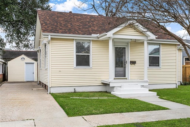 bungalow-style home with a front lawn and an outbuilding