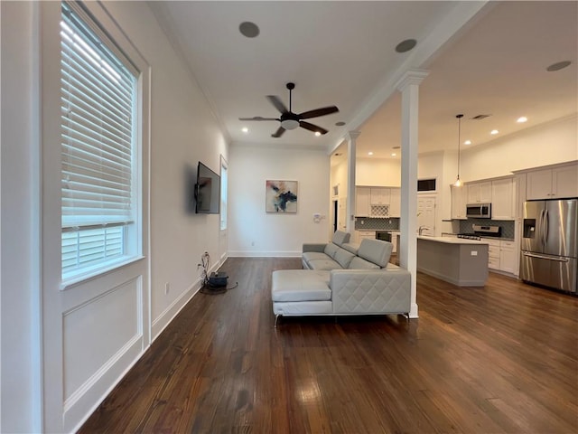 living room featuring ceiling fan, decorative columns, and dark hardwood / wood-style floors