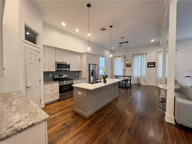 kitchen with hanging light fixtures, an island with sink, stainless steel appliances, and white cabinets