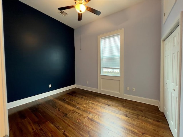 unfurnished bedroom featuring ceiling fan, a closet, and dark hardwood / wood-style flooring