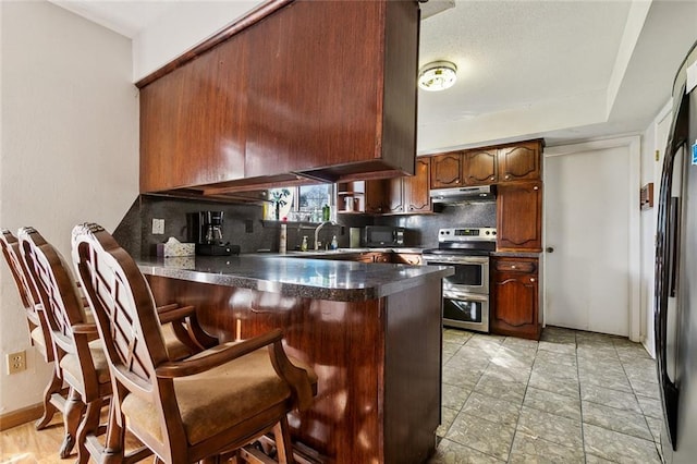 kitchen featuring sink, a breakfast bar, black appliances, kitchen peninsula, and decorative backsplash