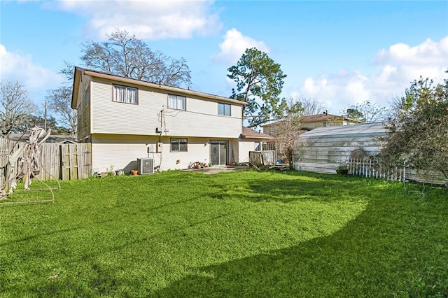 rear view of property with central AC unit and a yard