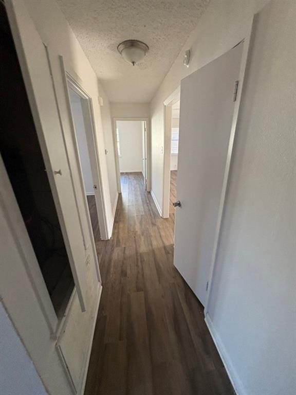 hallway with a textured ceiling and dark hardwood / wood-style floors