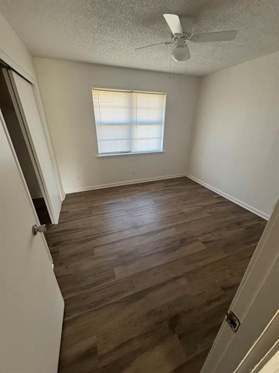 unfurnished bedroom with a textured ceiling, dark wood-type flooring, ceiling fan, and a closet