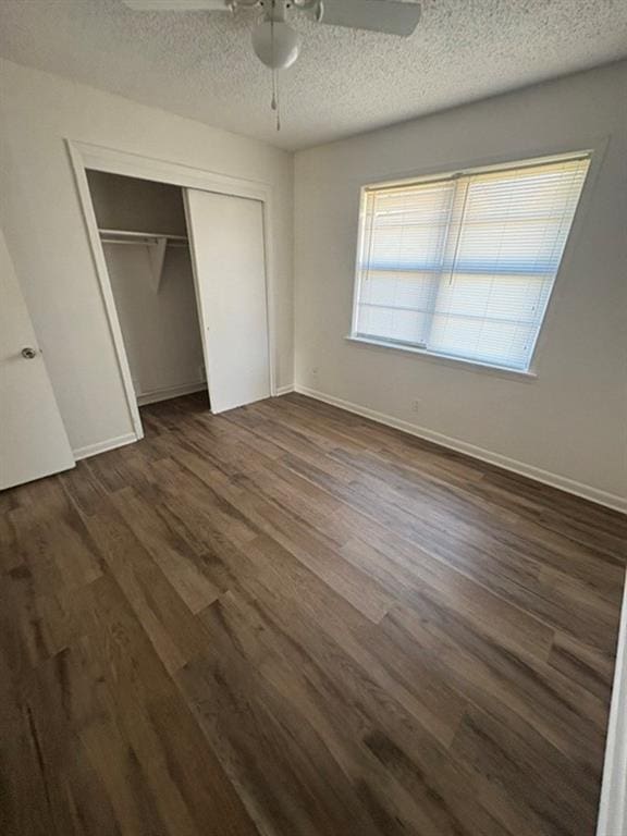 unfurnished bedroom with a textured ceiling, dark wood-type flooring, ceiling fan, and a closet