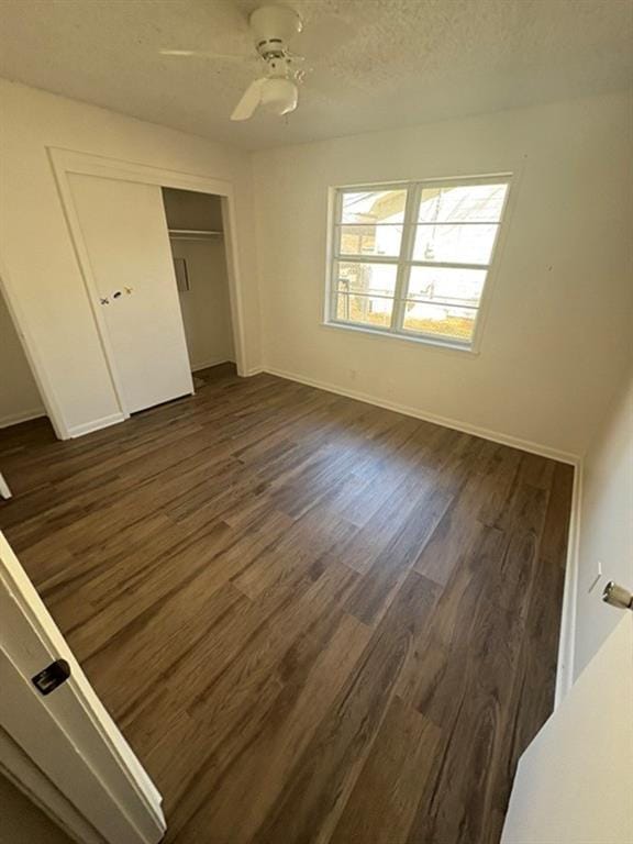 unfurnished bedroom featuring a textured ceiling, a closet, dark hardwood / wood-style floors, and ceiling fan