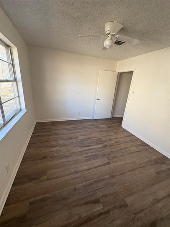 unfurnished room featuring ceiling fan, dark hardwood / wood-style floors, and a textured ceiling