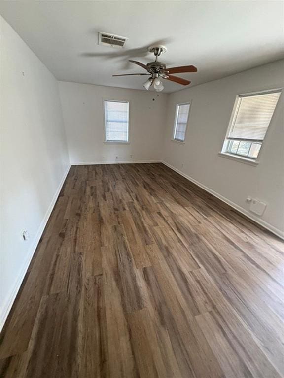 spare room with ceiling fan, dark wood-type flooring, and plenty of natural light