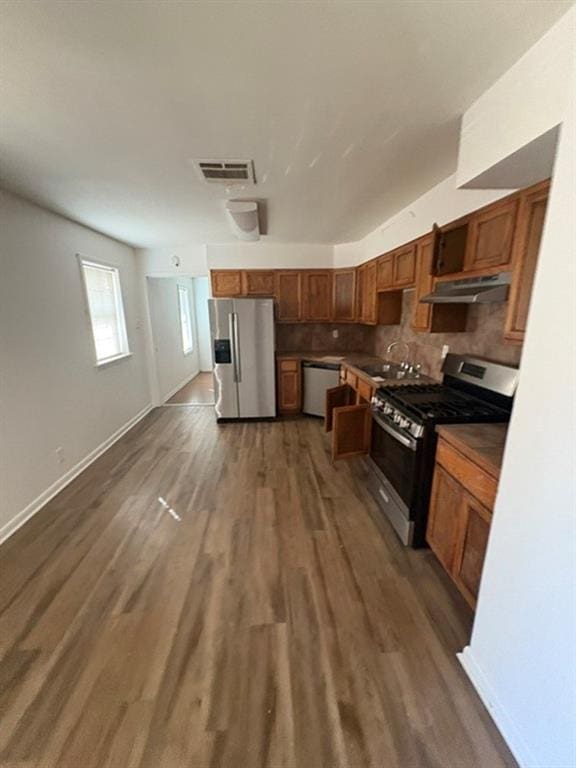 kitchen with dark hardwood / wood-style flooring, sink, stainless steel appliances, and backsplash