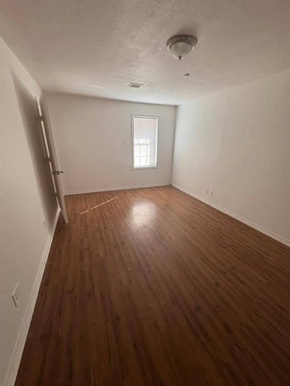 unfurnished room with dark hardwood / wood-style floors and a textured ceiling