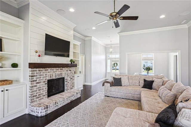 living room with a brick fireplace, crown molding, built in features, and dark hardwood / wood-style floors