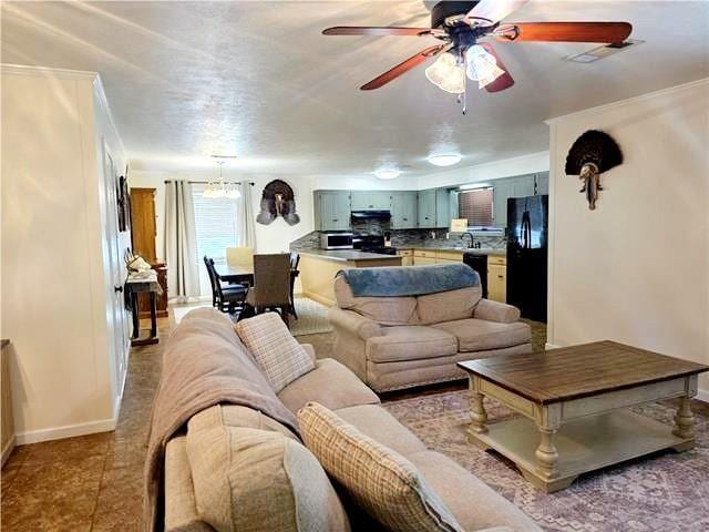 living room with ceiling fan with notable chandelier, sink, and tile patterned flooring