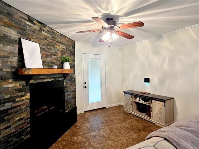 living room featuring a fireplace, crown molding, and ceiling fan