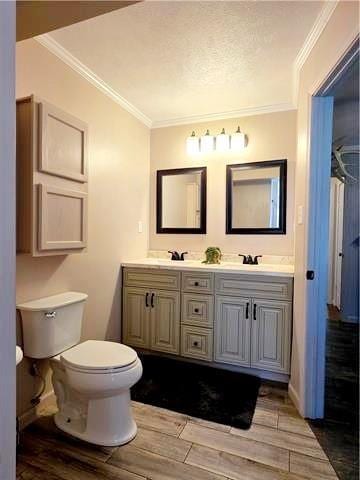 bathroom with crown molding, wood-type flooring, and vanity