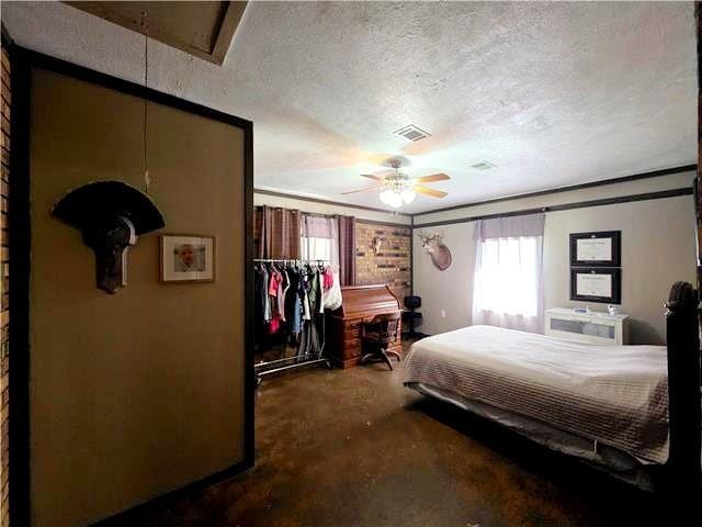 bedroom with ceiling fan, ornamental molding, a textured ceiling, and concrete floors