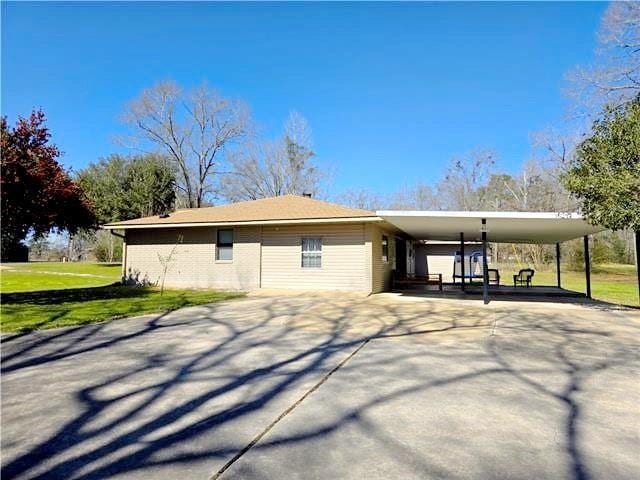 back of property featuring a lawn and a carport