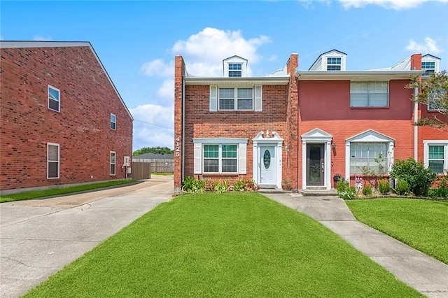 view of front of house with a front lawn, fence, and brick siding