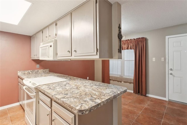 kitchen featuring tile patterned flooring, baseboards, light countertops, a skylight, and white appliances