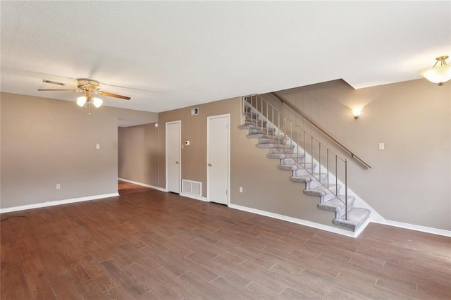 unfurnished living room featuring stairs, wood finished floors, visible vents, and baseboards