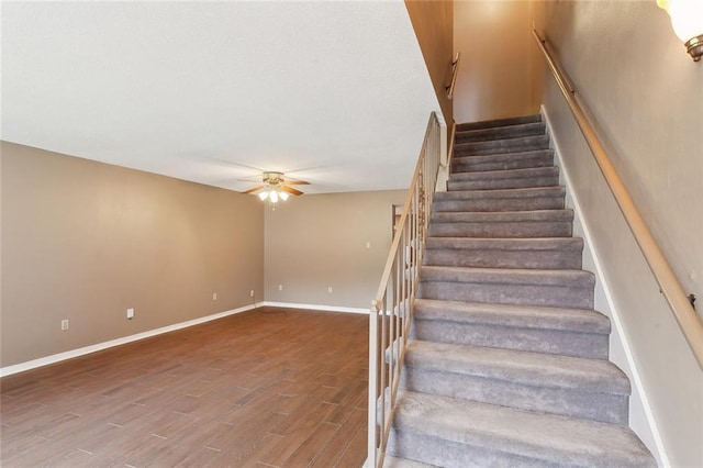 staircase with baseboards, a ceiling fan, and wood finished floors