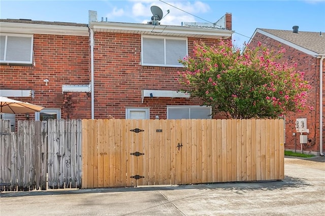 view of side of property featuring a gate, fence, and brick siding