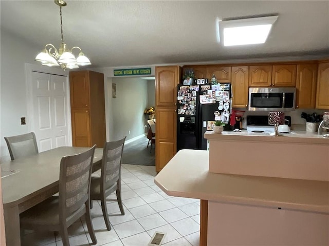 57428 Mainegra Rd, Slidell, LA 70460 - kitchen featuring black refrigerator with ice dispenser, stainless steel microwave, light tile patterned floors, range, and a notable chandelier