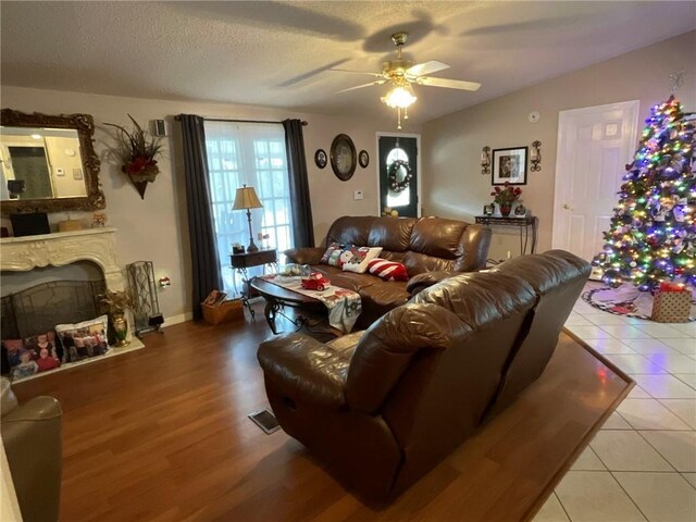 57428 Mainegra Rd, Slidell, LA 70460 - living area with ceiling fan, a fireplace, a textured ceiling, wood finished floors, and visible vents