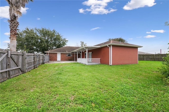 rear view of property featuring a lawn, a fenced backyard, and a gate