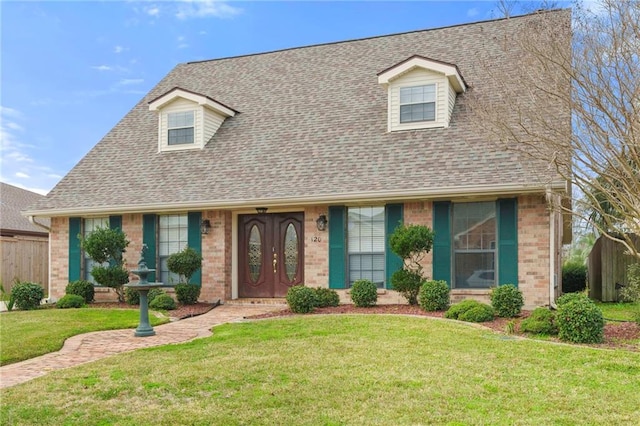 view of front of house with a shingled roof, fence, a front lawn, and brick siding