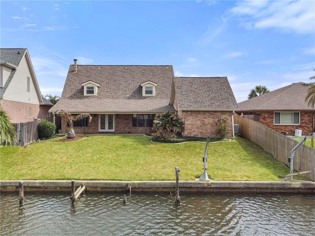 rear view of house with a lawn, brick siding, a water view, and roof with shingles