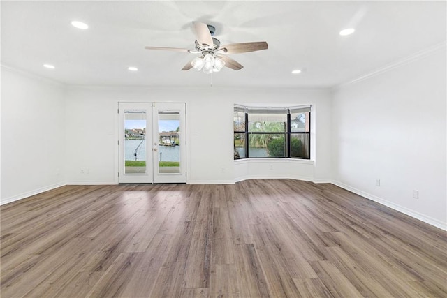 empty room with crown molding, wood finished floors, and a wealth of natural light