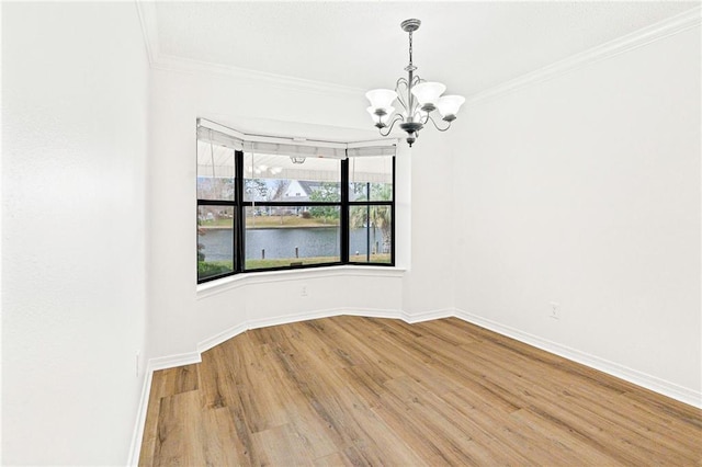 unfurnished room with a chandelier, baseboards, wood finished floors, and crown molding