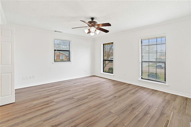 unfurnished room featuring a wealth of natural light, visible vents, crown molding, and wood finished floors