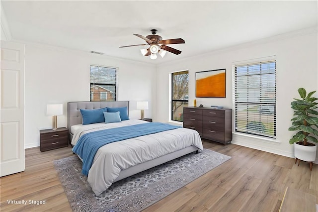 bedroom with visible vents, multiple windows, light wood-style floors, and crown molding