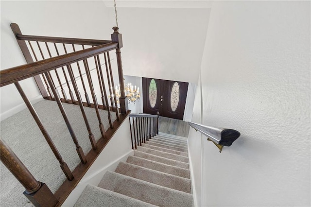 stairs with a notable chandelier and carpet floors